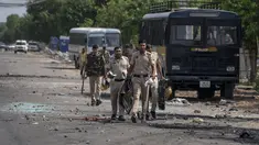 Pecahan kaca dan puing-puing berserakan di jalan saat polisi berpatroli setelah bentrokan komunal di Nuh di negara bagian Haryana, India, Selasa, 1 Agustus 2023. (AP Photo/Altaf Qadri)