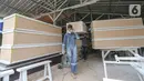 Pekerja membawa peti mati Covid-19 di Rawa Mekar Jaya, Serpong, Tangerang Selatan, Kamis (21/01/2021). Peti mati yang dijual dengan harga Rp 1 juta berbahan baku papan MDF didistribusi di wilayah Jabodetabek. (Liputan6.com/Fery Pradolo)