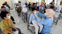 Paramedis dari Puskesmas Cinere membenahi masker murid kelas 1 saat kegiatan Bulan Imunisasi Anak Sekolah (BIAS) di SDI Al-Hidayah, Depok, Jawa Barat, Kamis (18/11/2021).  Sebanyak 100.719 siswa kelas I, II, dan V SD atau MI sederajat menjadi sasaran pemberian imunisasi. (merdeka.com/Arie Basuki)