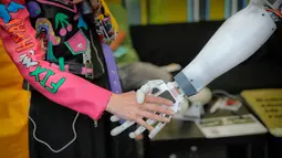 Seorang reporter berjabat tangan dengan robot InMoov rancangan Gael Langevin dalam pameran teknologi Bucharest, Romania (26/5). (AP Photo / Vadim Ghirda)