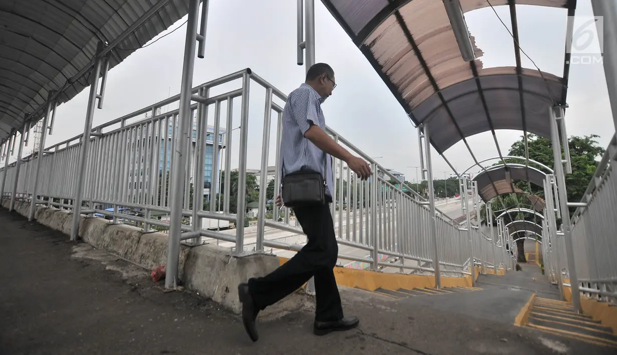 Pejalan kaki melintasi jembatan penyeberangan orang (JPO) di Jalan Yos Sudarso, Jakarta, Kamis (8/11). JPO akan semakin mengganggu kenyamanan dan keselamatan pejalan kaki apabila sedang hujan. (Merdeka.com/Iqbal Nugroho)