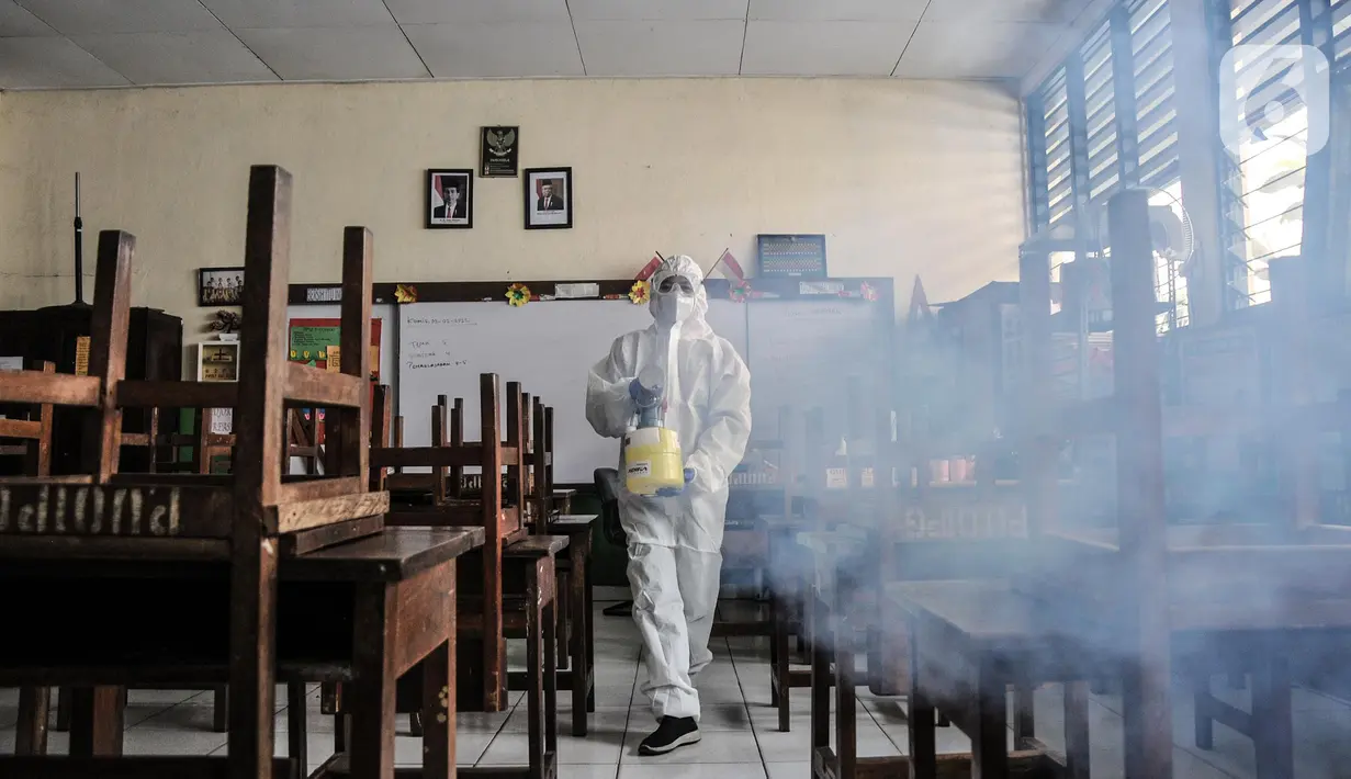 Petugas PMI menyemprotkan disinfektan sebagai upaya pencegahan COVID-19 di SDN Petojo Utara 01, Kecamatan Gambir, Jakarta, Kamis (3/2/2022). Pelaksanaan PTM 100 persen menjadi 50 persen berdasarkan SKB 4 Menteri seiring melonjaknya kasus COVID-19 di lingkungan sekolah. (merdeka.com/Iqbal S. Nugroho)