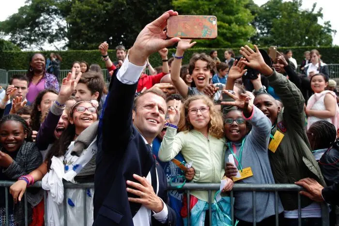 Presiden Prancis Emmanuel Macron berswafoto bersama anak-anak lain yang menghadiri upacara. (AP-Pool: Charles Platiau)