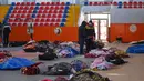 Orang-orang berjalan di antara jenazah korban yang dibaringkan di gedung olahraga kota, dua hari setelah gempa kuat melanda wilayah tersebut, di kota Kahramanmaras, Turki tenggara, Rabu (8/2/2023). Para kru penyelamat masih berusaha keras untuk menyelamatkan para korban lainnya yang berada di reruntuhan bangunan dengan kondisi cuaca yang buruk. (OZAN KOSE / AFP)
