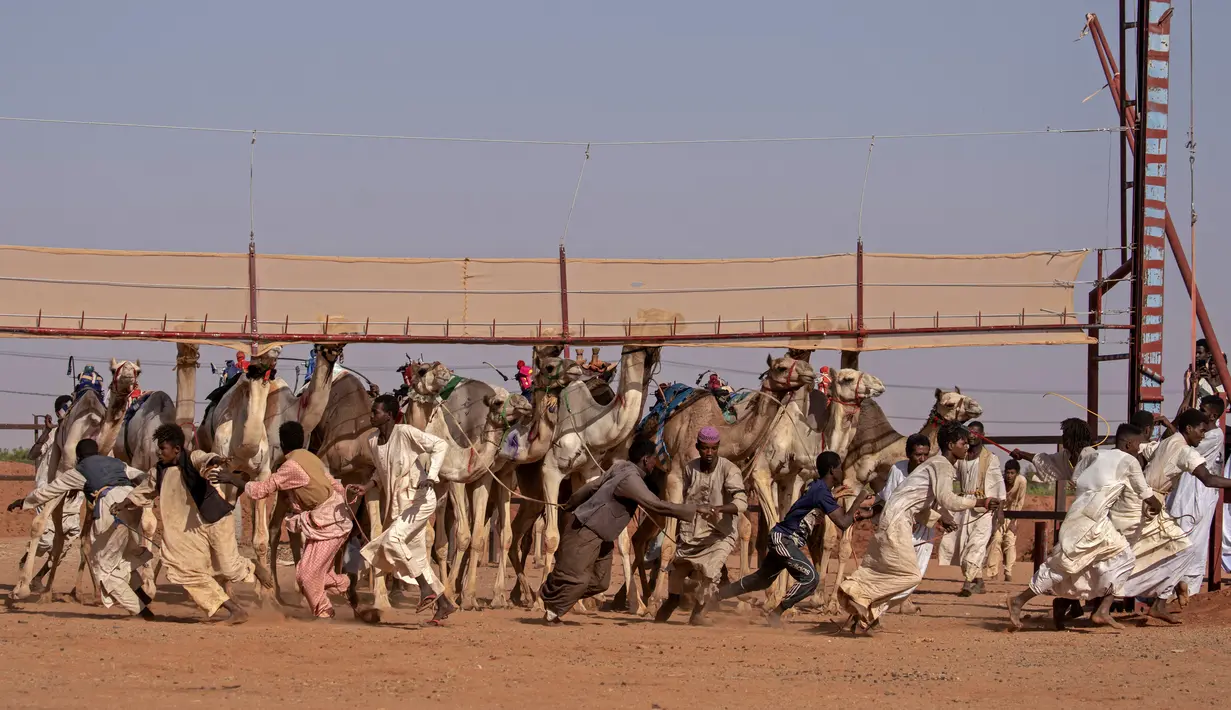 Petugas Sudan bergegas keluar dari trek menjelang balapan unta di dekat desa al-Ikhlas, barat kota Omdurman, 19 Maret 2021. Perlombaan diselenggarakan oleh keluarga suku tradisional yang memelihara unta dari desa setempat untuk melestarikan dan merayakan warisan budaya mereka. (ABDULMONAM EASSA/AFP)