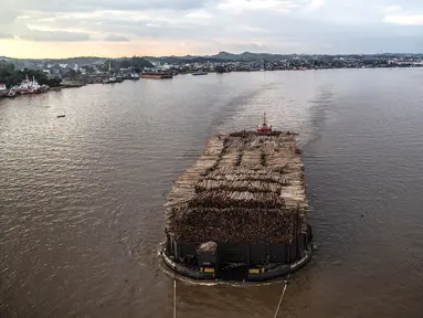 Sebuah kapal tongkang berisi kayu gelondongan ditarik di sepanjang Sungai Mahakam melewati Kota Samarinda, Kalimantan Timur, 4 November 2021. (ADITYA AJI/AFP)