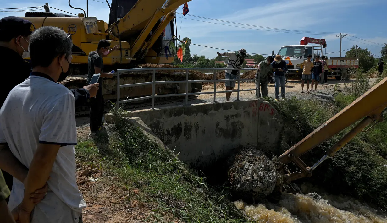 Pekerja kota mencoba memblokir kanal untuk melindungi rumah dari air banjir yang meningkat setelah hujan lebat di pinggiran Phnom Penh, Kamboja (26/10/2021). (AFP/Tang Chhin Sothy)