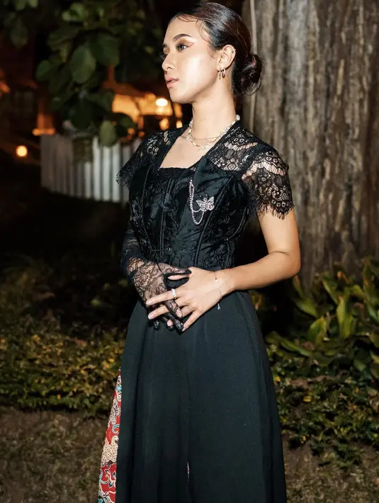 Melihat gaya anggun Rahmania dibalut outfit berwarna hitam. Bagian atasnya memiliki siluet seperti kebaya dipadu rok dengan sentuhan motif batik di satu sisinya. Perpaduan makeup bernuansa kecokelatan dan rambut yang digelung ke belakang menyempurnakan penampilannya secara keseluruhan. [Foto: Instagram/rahmaniaastrini]