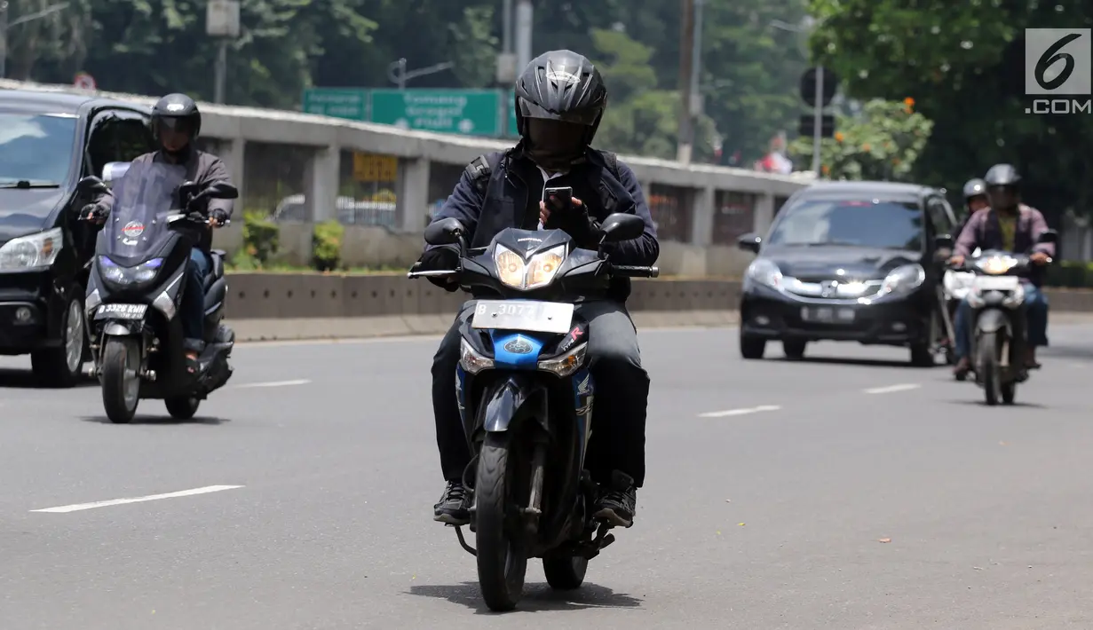 Warga mengoperasikan telepon seluler saat mengendarai sepeda motor di Jalan Gatot Subroto, Jakarta, Kamis (8/3). Menurut pihak kepolisian kecelakaan akibat penggunaan telepon genggam saat mengemudi kerap terjadi. (Liputan6.com/Arya Manggala)