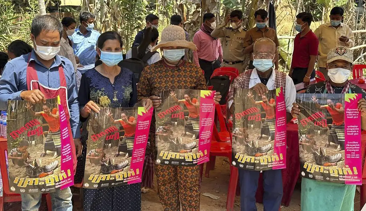 Penduduk desa Kamboja memegang poster untuk menyebarkan kesadaran akan ancaman virus H5N1 saat para ahli kesehatan berusaha mendidik mereka untuk menjaga kesehatan di Prey Veng, provinsi timur Kamboja, Kamis (23/2/2023). Gadis kecil di Kamboja itu jatuh sakit pada 16 Februari lalu dengan menderita demam, batuk dan sakit tenggorokan,  kemudian meninggal di rumah sakit, kata Departemen Pengendalian Penyakit Menular Kamboja pada Rabu. (Cambodia Ministry of Health via AP)
