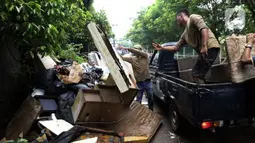 Petugas membuang barang milik warga di sepanjang jalan pascabanjir mulai surut di kawasan Kembangan, Jakarta Barat, Minggu (5/1/2020). Pasca banjir yang melanda hampir di kawasan Jakarta mulai surut, tumpukan sampah terlihat di sepanjang jalan dari rumah-rumah warga. (Liputan6.com/Johan Tallo)