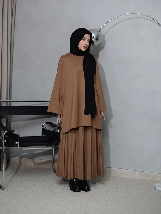 Padu padan tunik polos dan rok plisket warna cokelat, serta dilengkapi dengan hijab kaus warna hitam cocok untuk lebaran hari ke-2. [@emyaghnia]