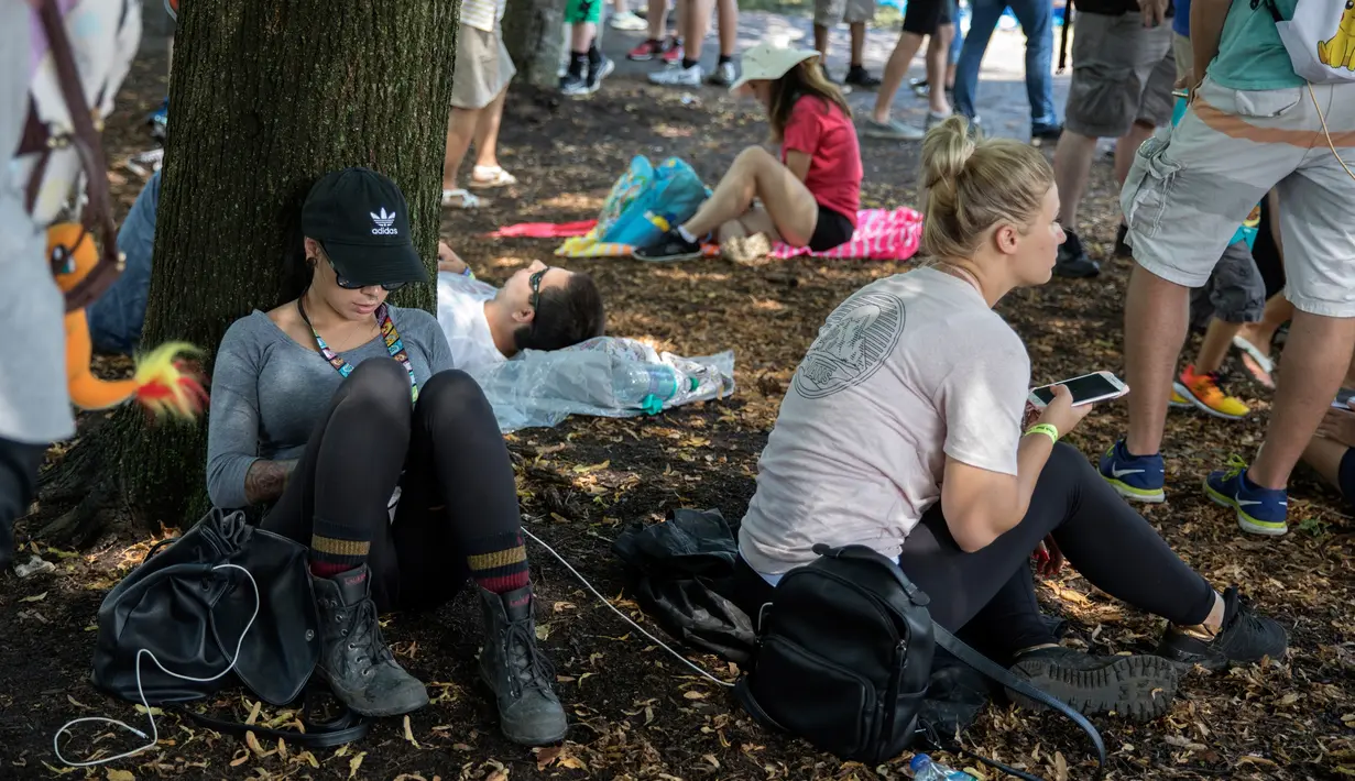 Dua peserta duduk di bawah pohon saat mengkuti Festival Pokemon Go di Giant Park, Chicago, Sabtu (22/7). Sebagai kompensasi, Niantic menawarkan Pakecoin senilai 100 dolar AS dan pengembalian harga tiket penuh untuk para peserta. (AP/Erin Hooley)