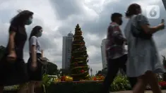 Warga DKI Jakarta melintas di dekat hiasan pohon Natal 2021 di Bundaran HI, Jakarta, Sabtu (25/12/2021). Libur Natal 2021 dimanfaatkan sebagian warga berfoto berlatar pohon Natal yang telah dihias atau berjalan-jalan ke mal untuk mengisi waktu berlibur bersama. (merdeka.com/Imam Buhori)