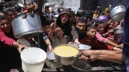 Para pengungsi Palestina berkumpul untuk mengambil makanan yang sudah dimasak dalam sebuah pembagian makanan di Jabalia, Jalur Gaza utara, pada 19 Mei 2025. (Bashar TALEB/AFP)
