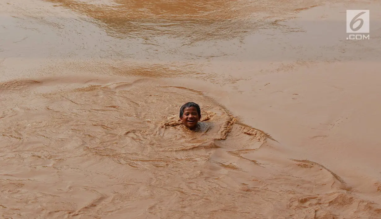 Seorang anak tersenyum saat berenang di Sungai Ciliwung yang meluap di kawasan Rawajati, Jakarta, Jumat (26/4). Tingginya volume debit air yang berasal dari Bogor tidak menyurutkan niat anak-anak itu untuk tetap berenang, meskipun berbahaya bagi keselamatan. (Liputan6.com/Immanuel Antonius)