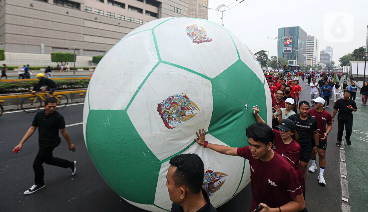 Masyarakat mengglindingkan bola raksasa dari Sarina ke Bundaran HI saat Trophy Experience Piala Dunia U-17 2023 di car free day (CFD) kawasan Jalan Thamrin, Jakarta, Minggu (15/10/2023). Kegiatan tersebut dalam rangka promosi ajang Piala Dunia U-17 2023 di Indonesia. (Liputan6.com/Faizal Fanani)