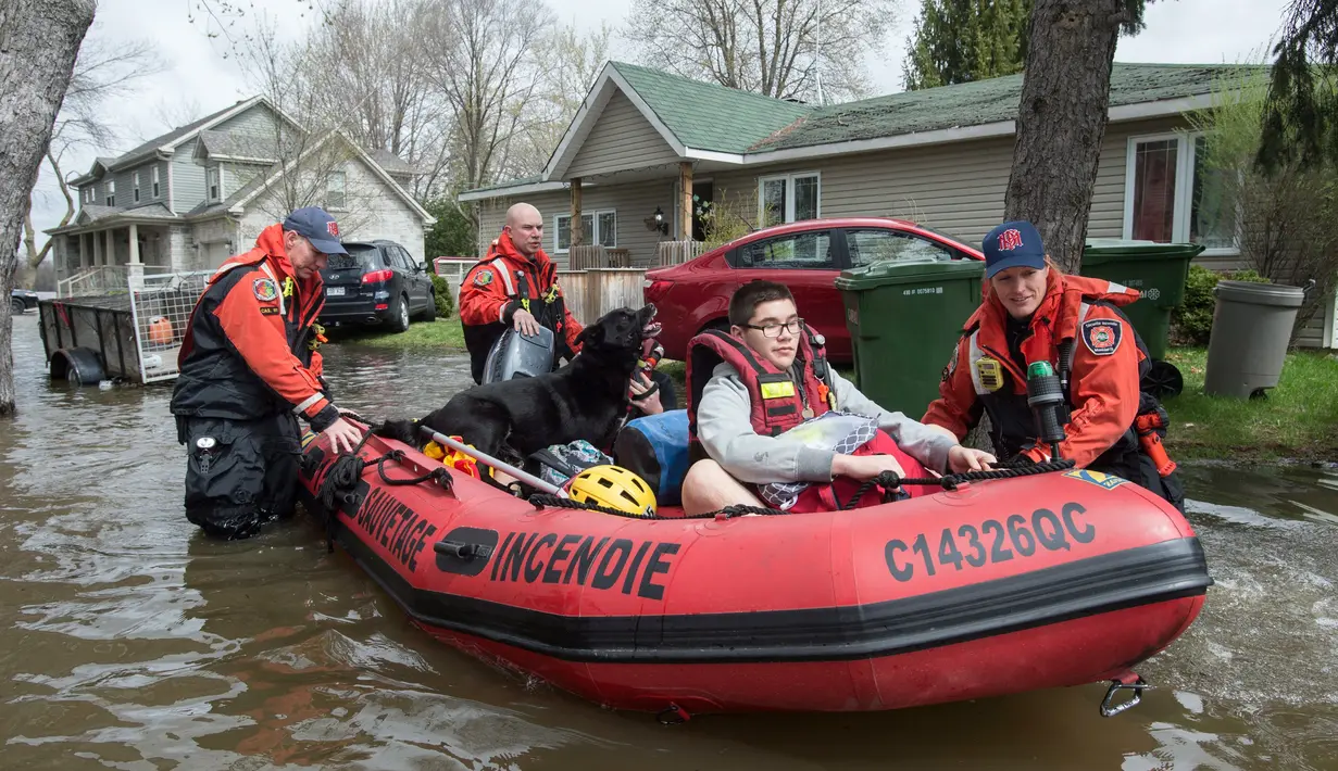 Petugas mengevakuasi warga Kota Montreal saat banjir melanda kawasan tersebut, Kanada, Selasa (9/5). Wali Kota Montreal, Denis Coderre mengatakan bahwa sudah ada 220 warga di kotanya yang dievakuasi dari rumah mereka. (AP Photo)