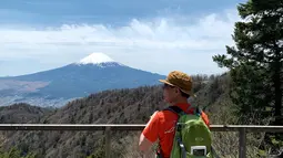 Seorang pejalan kaki melihat Gunung Fuji dari pinggiran kota Fujiyoshida, prefektur Yamanashi, pada Kamis (22/4/021). Prefektur Yamanashi terletak di sebelah barat Tokyo yang memiliki spot-spot wisata terkenal, salah satunya gunung tertinggi di Jepang, Gunung Fuji. (Behrouz MEHRI / AFP)
