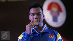 Lifter Lampung, Viky Aryanto memamerkan medali emas kelas 66 kg putra PON XIX di GOR Sabilulungan, Kab Bandung, Minggu (25/9). Viky merebut emas di kelas 66 kg dengan total angkatan 798 kg. (Liputan6.com/Helmi Fithriansyah)