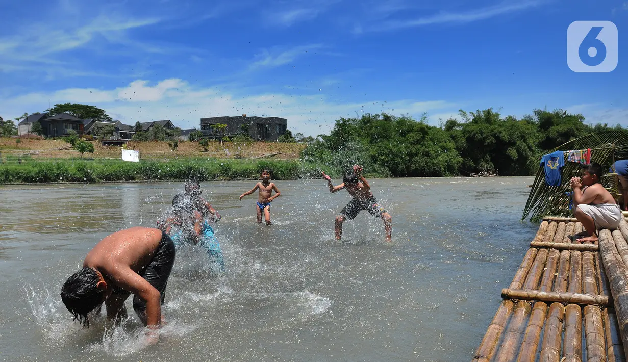 Anak-anak bermain pada aliran Sungai Cisadane di kawasan Keranggan, Setu, Tangerang Selatan, Banten, Minggu (20/3/2022). Cuaca panas terik dimanfaatkan mereka untuk berendam sambil bermain. (merdeka.com/Arie Basuki)