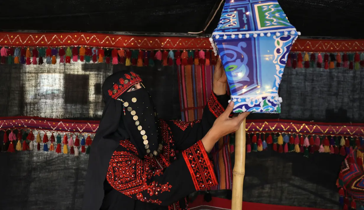 Seorang wanita menggantung lentera yang dikenal dalam bahasa Arab sebagai "Ramadhan Fanous" jelang bulan suci Ramadhan di Kota Gaza, Palestina, 31 Maret 2022. Ramadhan di Palestina akan dimulai pada akhir pekan ini. (MOHAMMED ABED/AFP)