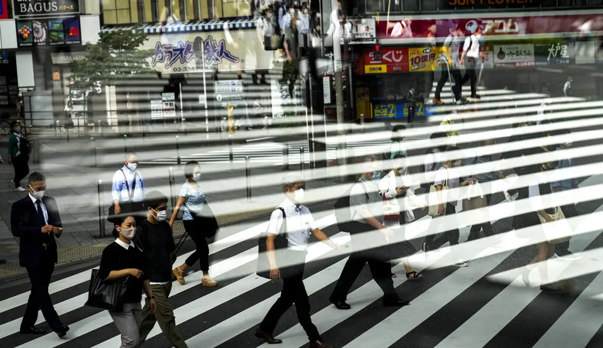 Penumpang tercermin di jendela bus saat mereka menyeberang jalan di Tokyo, Kamis (15/7/2021). Olimpiade Tokyo 2020 yang tertunda pandemi corona dibuka pada 23 Juli tanpa penonton di sebagian besar tempat. (AP Photo /Jae C.Hong)