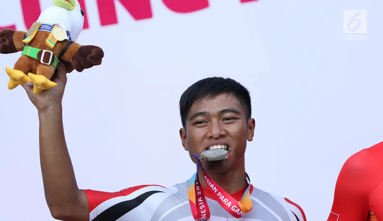 Atlet ParaCycling, Sufyan Saori menggigit medali perak nomor Mens C5 Individual Time Trial Road Race Asian Para Games 2018 di Sirkuit Sentul, Bogor, Senin (8/10). Sufyan Saori berhasil merebut medali perak. (Liputan6.com/Helmi Fithriansyah)