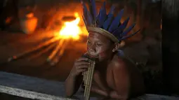Salah satu warga suku Amazon Tatuyo terlihat memainkan musik tradisional di desanya, Rio Negro (Black River) dekat salah satu kota penyelenggara pertandingan Piala Dunia 2014, Manaus City, Brasil  (23/6/2014). (REUTERS/Andres Stapff)