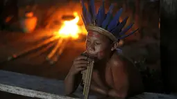 Salah satu warga suku Amazon Tatuyo terlihat memainkan musik tradisional di desanya, Rio Negro (Black River) dekat salah satu kota penyelenggara pertandingan Piala Dunia 2014, Manaus City, Brasil  (23/6/2014). (REUTERS/Andres Stapff)