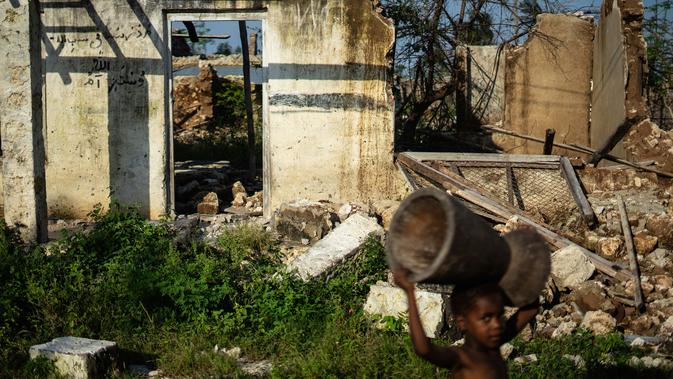 Seorang gadis melintasi sebuah madrasah yang hancur akibat topan Kenneth pada bulan lalu di desa Kumwamba, Pulau Ibo, 13 Mei 2019. Umat Islam di Mozambik melalui bulan Ramadan dengan badai yang menyebabkan sebagian besar masjid hancur dan persediaan makanan sangat terbatas. (Zinyange Auntony/AFP)