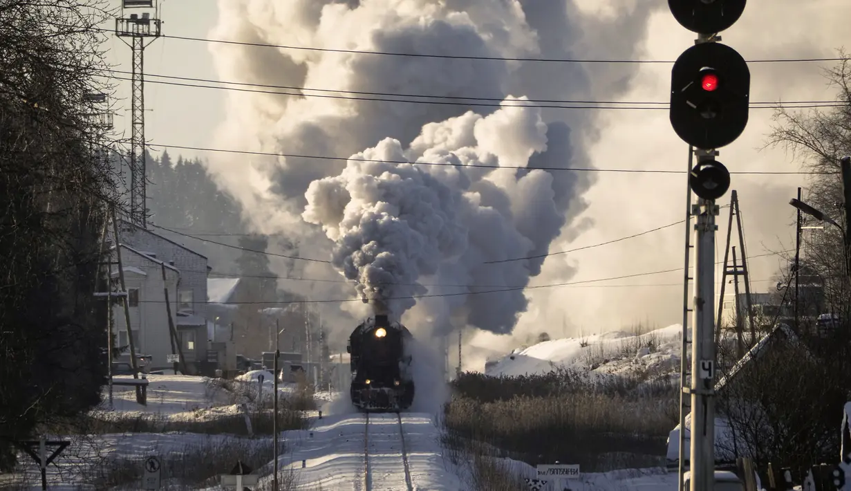 Sebuah lokomotif uap era Soviet menarik kereta retro di taman alam Ruskeala, sekitar 200 km (125 mil) di utara St. Petersburg, Rusia (17/2/2021). Kereta retro bertenaga uap tersebut beroperasi setiap hari di perbatasan Rusia dengan Karelia. (AP Photo/Dmitri Lovetsky)