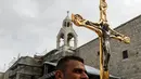 Diaken dan pendeta Katolik Roma berjalan sambil membawa Salib saat prosesi perayaan Natal di Manger Square di luar Gereja Nativity di Kota Betlehem, Palestina, Minggu (24/12). (AFP/Musa Al Shaer)