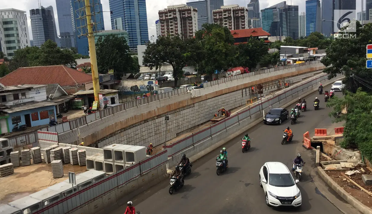 Kendaraan melintas di samping pembangunan proyek underpass Mampang-Kuningan, Jakarta, Senin (29/1). Underpass dengan panjang 860 meter ini kemungkinan besar baru bisa rampung pada April 2018 mendatang. (Liputan6.com/Immanuel Antonius)
