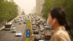 Seorang wanita yang memakai masker wajah berjalan melintasi jembatan penyeberangan saat badai pasir di Beijing, China, Kamis (6/5/2021). Debu dan badai pasir akhir musim semi mengirim indeks kualitas udara melonjak di Ibu Kota China pada hari ini. (AP Photo/Mark Schiefelbein)