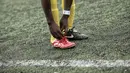 Pemain Mali sedang membenahi tali sepatunya saat bermain melawan Guinea dalam turnamen sepak bola untuk kaum migran dan orang asing bertajuk "Balon Mundial" yang dihelat 6 Juni-5 Juli 2015 di Turin, Italia. (AFP PHOTO/MARCO BERTORELLO)