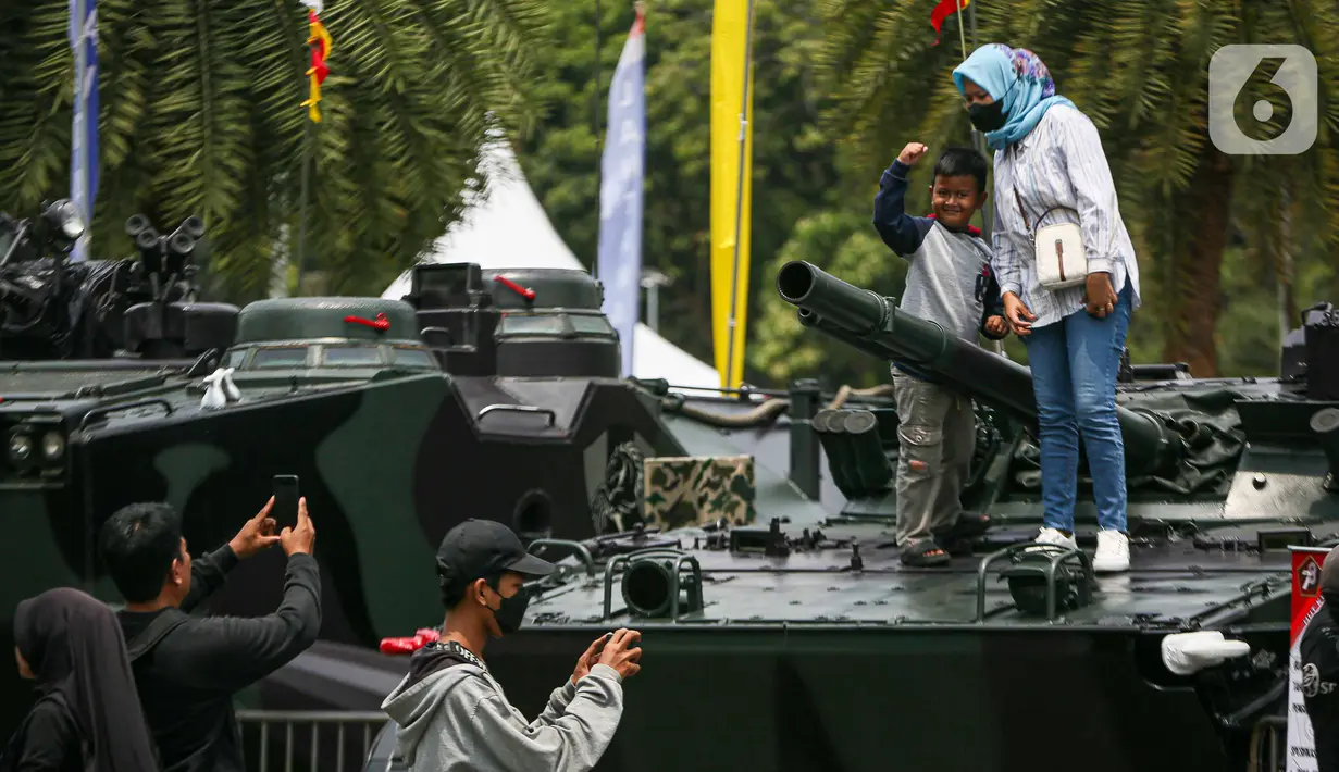 Warga berfoto di atas kendaraan milik TNI saat pameran alat utama senjata (alutsista) di Lapangan Monumen Nasional (Monas) Jakarta, Minggu (24/9/2023). (Liputan6.com/Faizal Fanani)