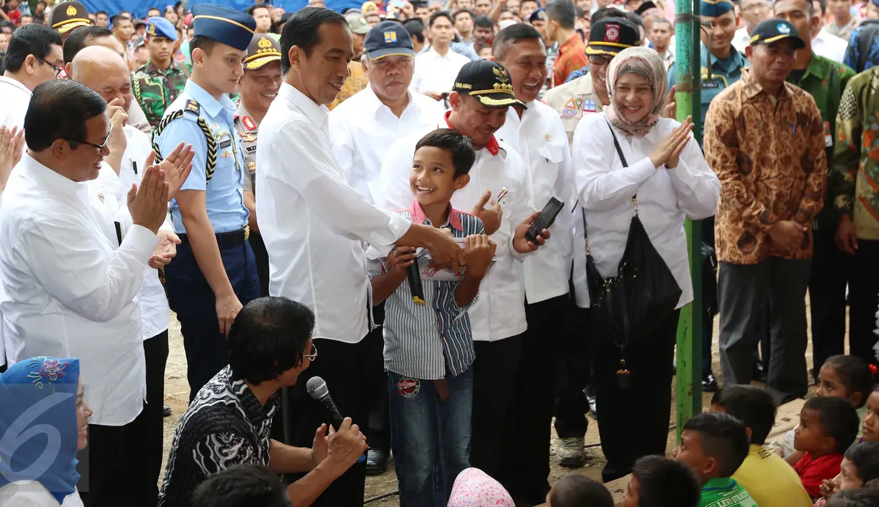 Presiden Jokowi memberikan hadiah kepada seorang anak yang menjawab pertanyaan saat meninjau tenda pengungsian korban gempa Aceh di Pidie Jaya, Jumat (9/12). Dalam kunjungan itu, Jokowi membagikan buku tulis untuk anak-anak. (Liputan6.com/Angga Yuniar)