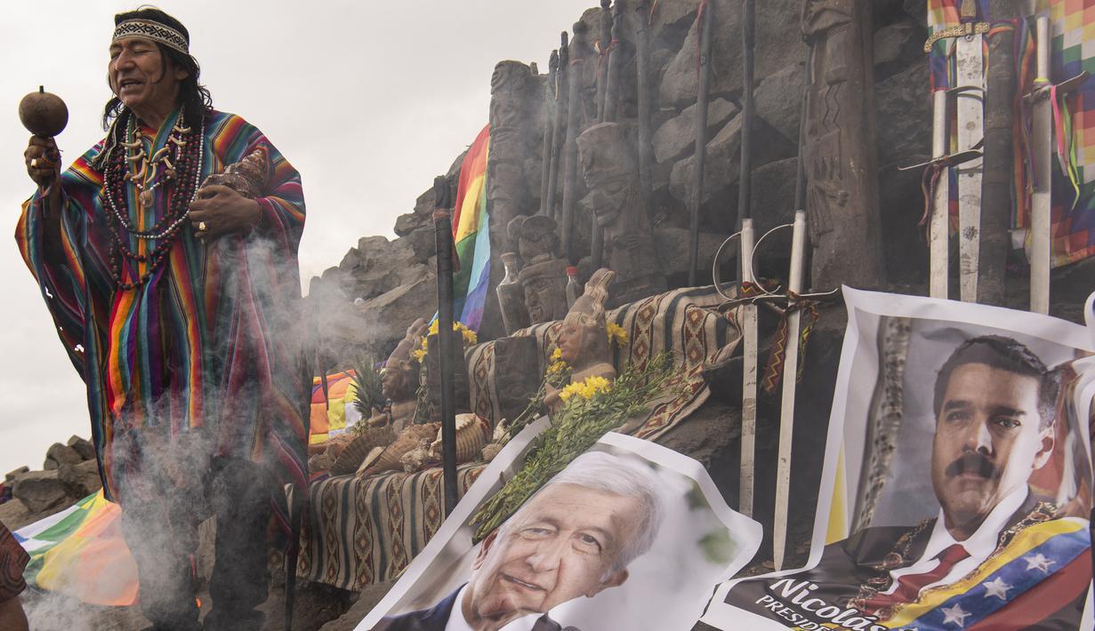 Dukun Peru melakukan ritual ramalan untuk prediksi tahun 2022 sebelum Malam Tahun Baru di samping poster Presiden Andres Manuel Lopez Obrador (kiri) dan Nicolas Maduro dari Venezuela, di bukit San Cristobal di Lima, Peru (29/12/2021). (AFP/Ernesto Benavides)