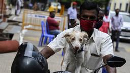 Seorang pria tiba dengan sepeda motor untuk menyuntik anjing peliharaannya dengan dosis vaksin antirabies pada kesempatan Hari Rabies Sedunia di Rumah Sakit Universitas Hewan Tamil Nadu, Chennai, Rabu (29/9/2021). Hari Rabies Sedunia diselenggarakan pada 28 September. (Arun SANKAR/AFP)
