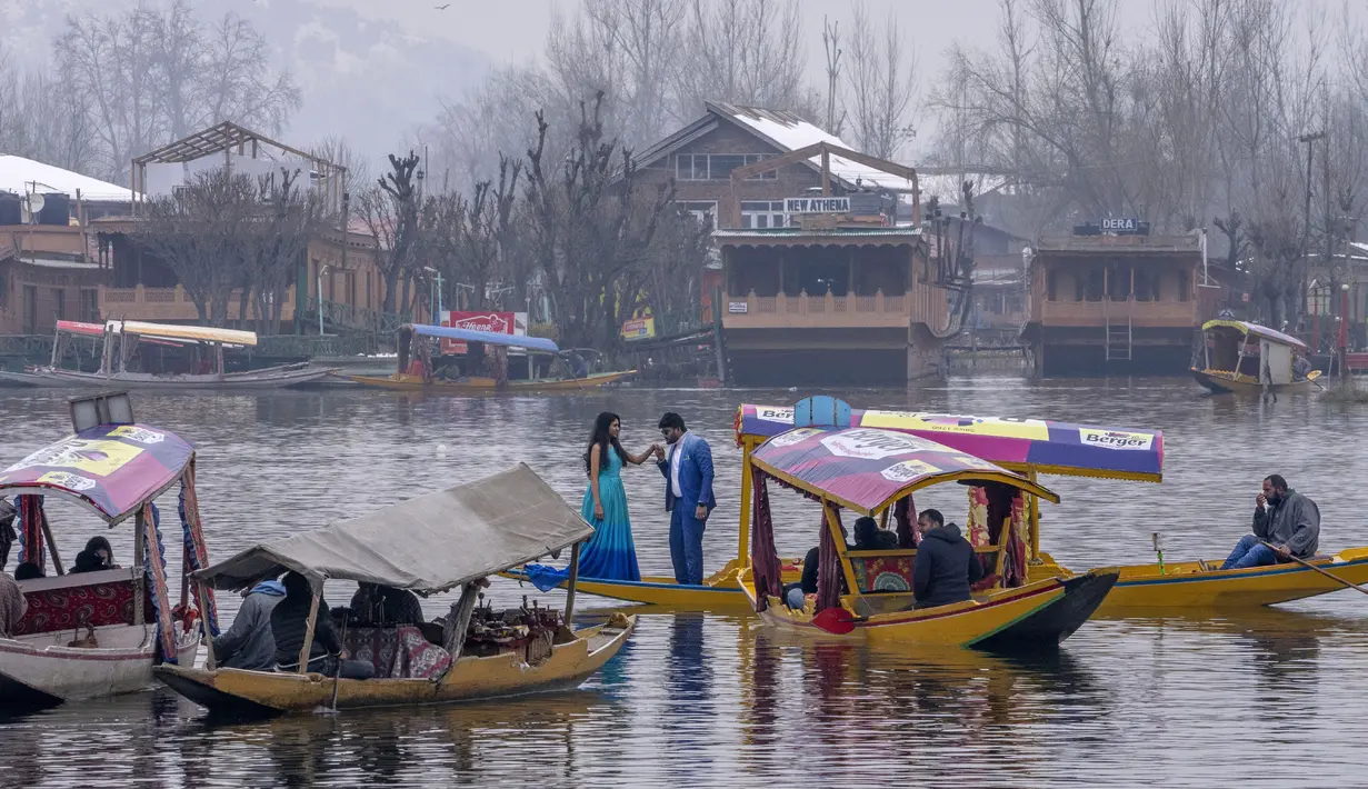 Turis berfoto sambil berdiri di atas gondola tradisional di Danau Dal di Srinagar, Kashmir yang dikuasai India pada 25 Februari 2022. Perlahan tapi pasti, kehidupan di Asia Selatan kembali normal dan orang-orang berharap yang terburuk dari pandemi COVID-19 ada di belakang mereka (AP Photo/Dar Yasin)