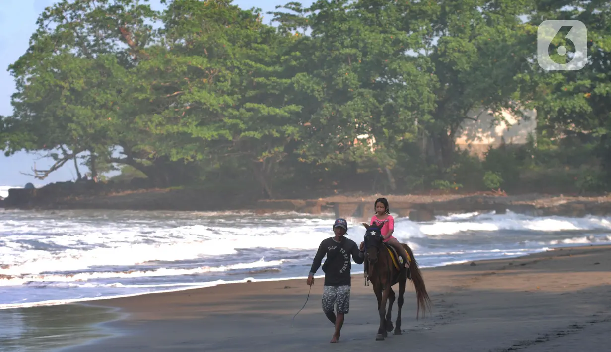 Seorang anak menaiki kuda di pinggir pantai di kawasan Pantai Karang Naya, Pelabuhan Ratu, Sukabumi, Selasa (1/6/2021). Walaupun liburan lebaran telah usai sejumlah pantai di kawasan Pelabuhan Ratu masih dipadati pengunjung yang berasal dari Kota Jakarta dan Jawa Barat.(merdeka.com/Arie Basuki)