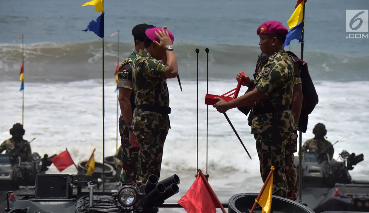 Panglima TNI Marsekal Hadi Tjahjanto (kiri) memakai baret ungu sebagai tanda telah menjadi warga kehormatan Korps Marinir di Pantai Nganteb, Malang, Jawa Timur, Kamis (22/2). (Liputan6.com/HO/Marinir TNI-AL)