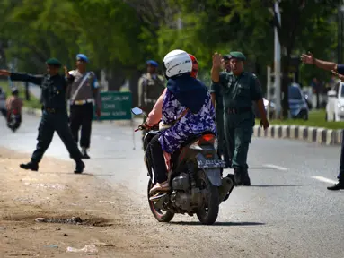 Polisi syariah memberhentikan pengendara yang terjaring razia busana muslim di sepanjang jalan Lambaro, provinsi Aceh, Selasa (23/7/2019). Aceh merupakan satu-satunya provinsi di Indonesia yang memberlakukan hukum Syariat Islam bagi warganya. (Photo by CHAIDEER MAHYUDDIN / AFP)