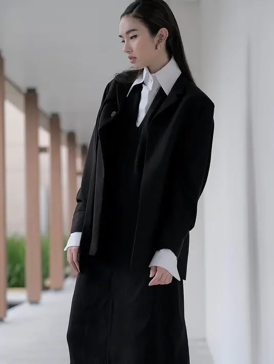 Tampil dengan style oversize tidak menghalangi elegansi dari seorang Nong Poy. Ia tampak mengenakan kemeja putih yang dilapisi blazer kebesaran dan midi skirt serba hitam. [@poydtreechada]
