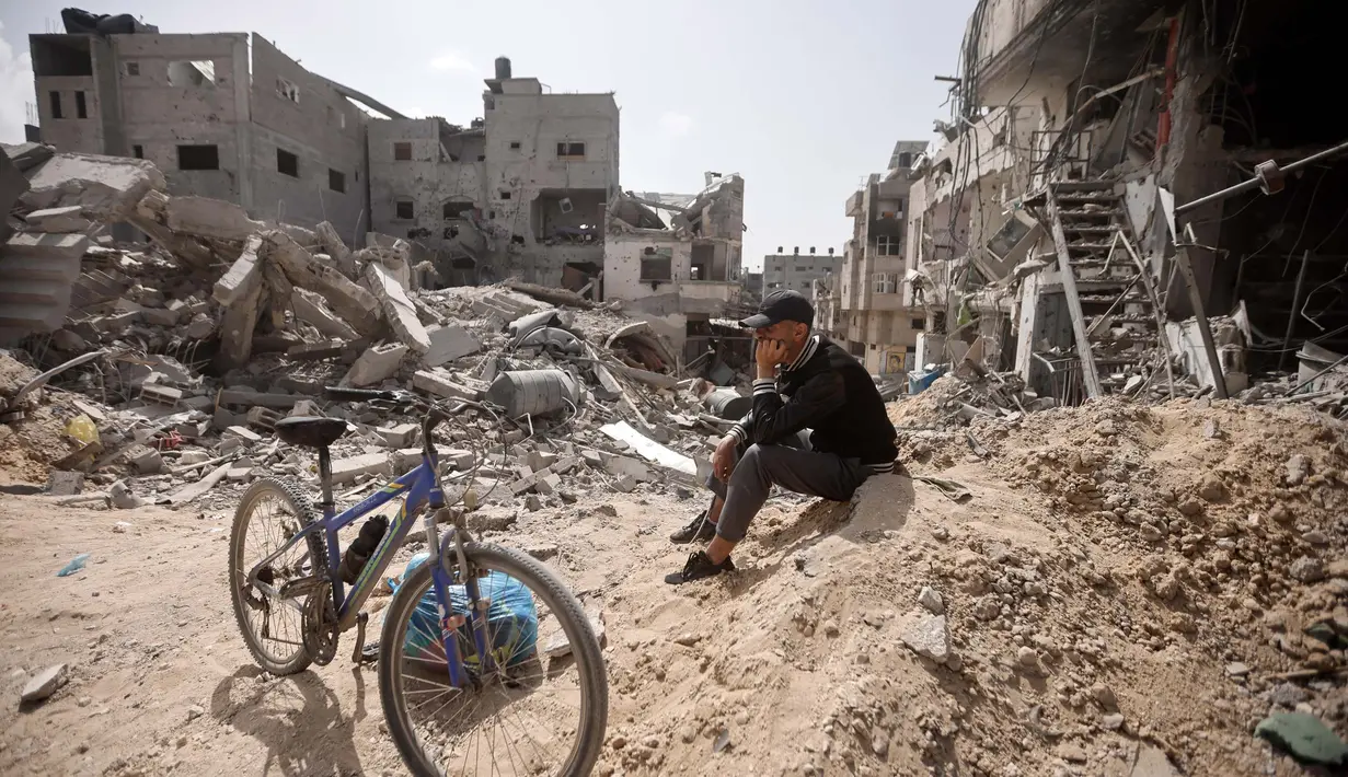 Seorang warga Palestina duduk di antara puing-puing bangunan yang hancur setelah pasukan Israel meninggalkan Khan Younis, Jalur Gaza, Rabu, 6 Maret 2024. (AP Photo/Mohammed Dahman)