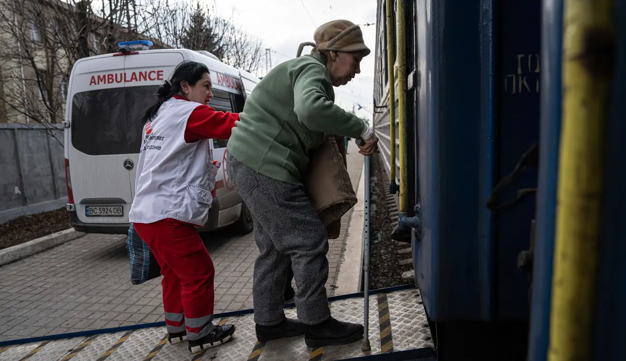 Pekerja Medecins Sans Frontieres (MSF) atau Doctors Without Border membantu seorang wanita masuk ke dalam kereta medis MSF saat mengevakuasi pasien dari dekat garis depan pertempuran ke daerah yang lebih aman di stasiun kereta di Pokrovsk, Ukraina, 7 Maret 2023. MSF merupakan kereta medis khusus yang dapat membawa pasien dari bagian timur Ukraina ke rumah sakit di bagian barat. (AP Photo/Evgeniy Maloletka)