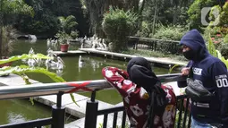 Wisatawan mengamati burung pelikan di Taman Margasatwa Ragunan, Jakarta Selatan, Sabtu (26/12/2020). Kawasan Ragunan pada libur panjang Natal 2020 ini terpantau cukup ramai meski tak seramai di hari sebelum Covid-19 merebak di Indonesia ini. (Liputan6.com/Herman Zakharia)