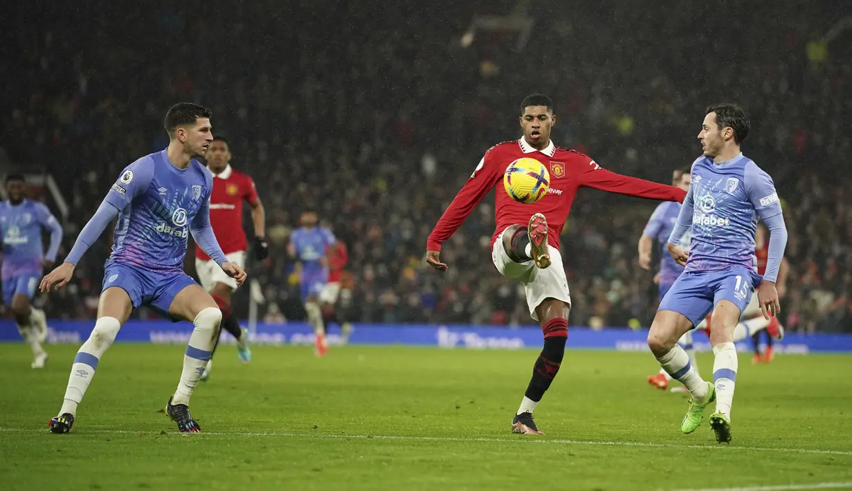 Penyeranga Manchester United, Marcus Rashford mengontrol bola dari kawalan dua pemain Bournemouth, Chris Mepham dan Adam Smith pada pertandingan lanjutan Liga Inggris di Old Trafford di Manchester, Inggris, Rabu (4/1/2023). Tambahan tiga poin membuat MU kukuh di posisi keempat klasemen Liga Inggris dengan 35 poin. (AP Photo/Dave Thompson)