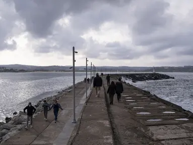 Orang-orang berjalan di tepi pantai di Sile, sebuah kota nelayan kecil sekitar 70 kilometer dari Istanbul, Turki, pada 7 Desember 2020. Kekhawatiran akibat pandemi COVID-19 menyebabkan semakin banyak penduduk Istanbul pindah ke distrik tepi pantai terpencil kota tersebut. (Xinhua/Osman Orsal)